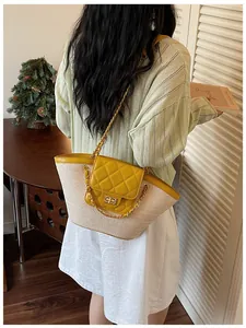 Vue de dos d'une femme portant un sac panier tressé jaune matelassé avec une chaîne