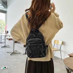 Model wearing a vintage black washed denim mini backpack in a cozy cafe indoor setting.