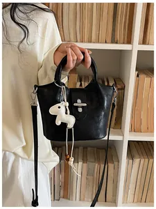 Vue détaillée d'un sac seau noir vintage avec un joli charm de cheval blanc à la main