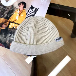 Detailed view of off-white ribbed knit child beanie featuring a stylish 'PPSW' woven label