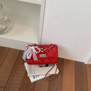 Detailed view of a red quilted crossbody bag with decorative lace bow and pearl accents
