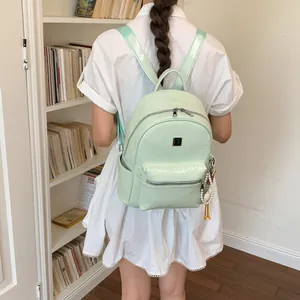 Primo piano di un elegante zaino in pelle intrecciata verde menta indossato da una studentessa