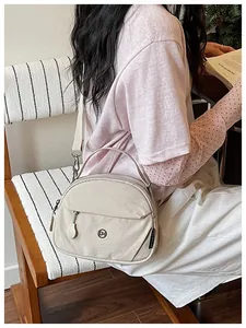 Bolso bandolera de nailon beige con correa mostrado en un entorno de estilo de vida