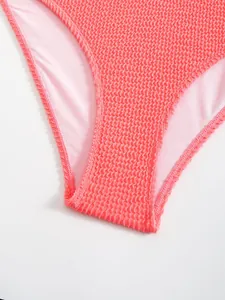 Primo piano del tessuto seersucker rosa corallo di questo sexy costume intero da donna.