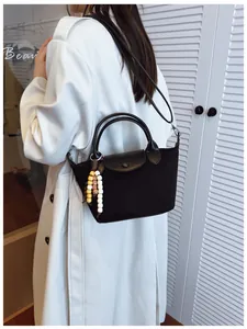 Vue arrière d'un mannequin avec un sac à main noir élégant et un charm en perles.