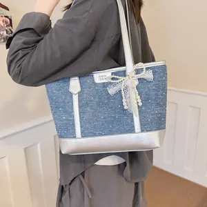 Femme portant un sac cabas en denim avec garniture argentée et un nœud en perles