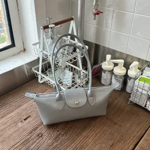 Sac à bandoulière gris élégant en forme de dumpling sur une table en bois rustique