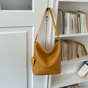 Detail van gele geweven hobo tas met retro textuur en grote capaciteit voor dames