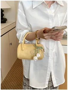 Elegant yellow cylinder pillow handbag with floral and pearl charms shown in daily use scene