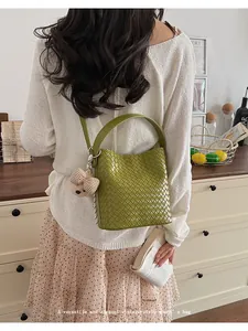 Lifestyle shot of a vintage green woven bucket bag worn by a model in a cozy room