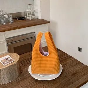 Detailansicht einer orangefarbenen, karierten Damen-Eimertasche in einer rustikalen Küche