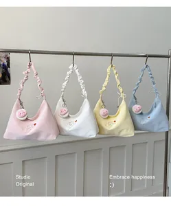 Cuatro bolsos hobo pastel con asas fruncidas colgados en un perchero de estudio.