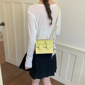 Stylish light yellow small square crossbody bag with decorative scarf accessory