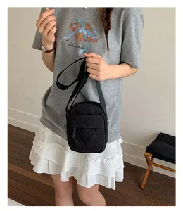 Casual black nylon crossbody bag worn by model in a minimalist indoor setting