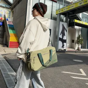 Stylish olive green large duffel bag shown in a fashionable urban lifestyle street scene.