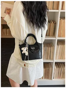 Vue lifestyle d'un sac seau noir chic porté avec une tenue blanche dans une bibliothèque