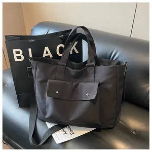Detailed view of black canvas tote bag with front pocket and adjustable shoulder strap