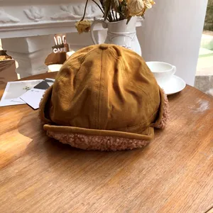 Ginger trapper hat with soft sherpa ear flaps placed on a rustic wooden table scene