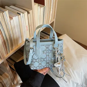 Detailed macro view of light blue denim tote bag featuring silver studs and star charm