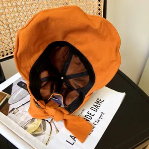 Detalle del interior de un sombrero de sol de algodón naranja con lazo elegante.
