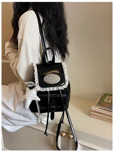 Detail view of a black faux leather backpack with delicate white lace trim and star charm
