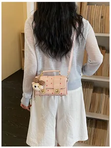 Back view of a vintage pink polka dot crossbody bag with a cute bear charm