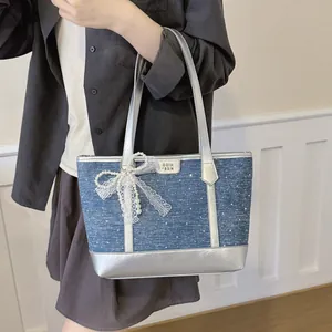 Gros plan d'un sac cabas bleu en denim avec garniture argentée et nœud en perles.