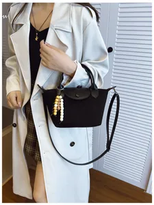 Mannequin portant un petit sac dumpling noir avec un charm en perles.