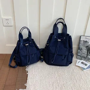 Comparación de dos mochilas de lona azul marino con cordón en tamaños pequeño y grande.
