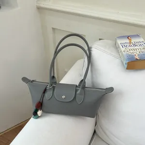 Élégant sac à bandoulière gris minimaliste posé sur un canapé blanc avec accessoires