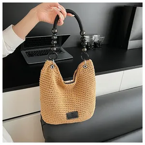 Close-up of a hand-woven khaki bucket bag featuring a stylish black beaded handle