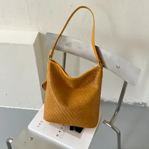 Gele gevlochten emmertas aan een minimalistische zilveren stoel met gedetailleerde textuur.