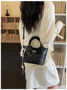 Vue détaillée d'un sac seau vintage noir avec un fermoir rotatif argenté et un charme d'ours.