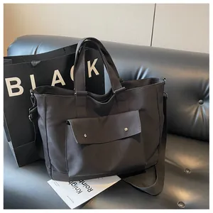 Large capacity black canvas tote bag shown in a stylish lifestyle indoor setting.
