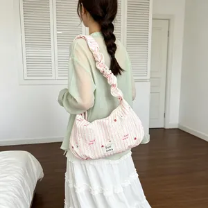 Close-up of a pink striped hobo dumpling bag with ruffled strap on a model back view
