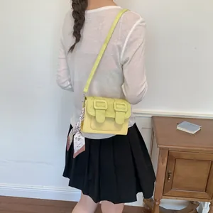 Model wearing a stylish yellow crossbody square bag with a decorative scarf