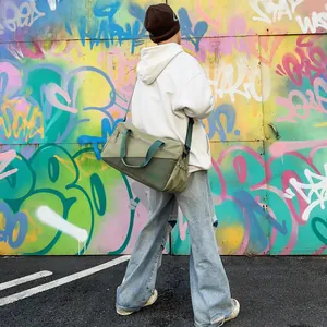 Model wearing a green olive casual shoulder bag in front of a graffiti wall