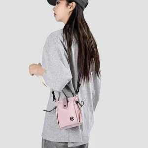 Vue détaillée d'un mini sac à bandoulière rose décontracté porté par un mannequin en gris