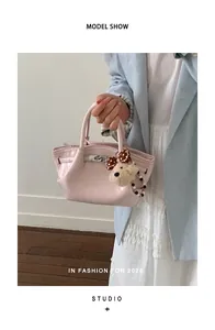 Dettaglio di un'elegante borsa a mano in vernice rosa con ciondolo a forma di orso