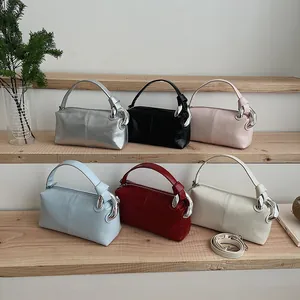 Vintage pillow bags in various colors displayed on wooden stairs with silver hardware.