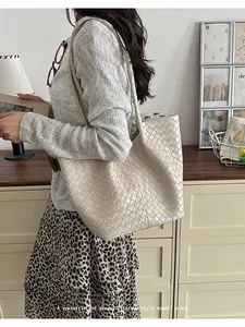 Side view of a woman wearing an elegant woven tote bag in a stylish indoor setting