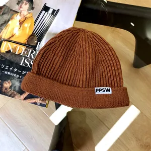 Close-up detail of children's brown ribbed knit beanie with white PPSW letter label