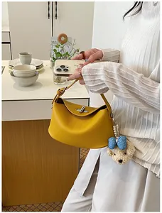 Detailed view of yellow pebbled leather bucket handbag featuring a cute dog charm