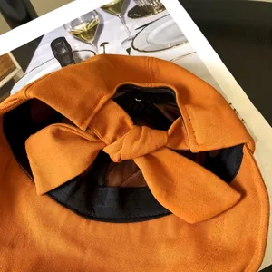 Primer plano de un sombrero de sol terracota con elegante lazo y tela texturizada.