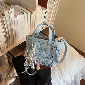 Close-up of light blue denim bucket bag with silver rivet patterns and star charms