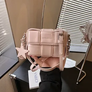 Close-up detail of a soft pink woven texture square crossbody bag with a star charm