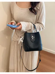 Sac seau classique en cuir noir porté par un mannequin pour un look rétro chic.