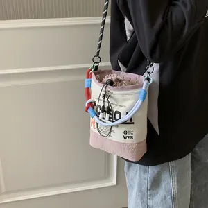 Detailansicht einer stylischen Canvas-Beuteltasche mit bunten Seilgriffen, schräg getragen.