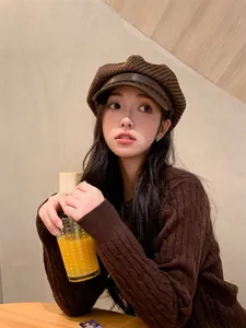 Close-up of a vintage brown striped baker boy hat worn by a model in a cozy cafe setting.