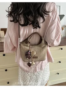 Détail d'un sac à main vintage en paille tressée avec breloques porté à l'épaule pour femme